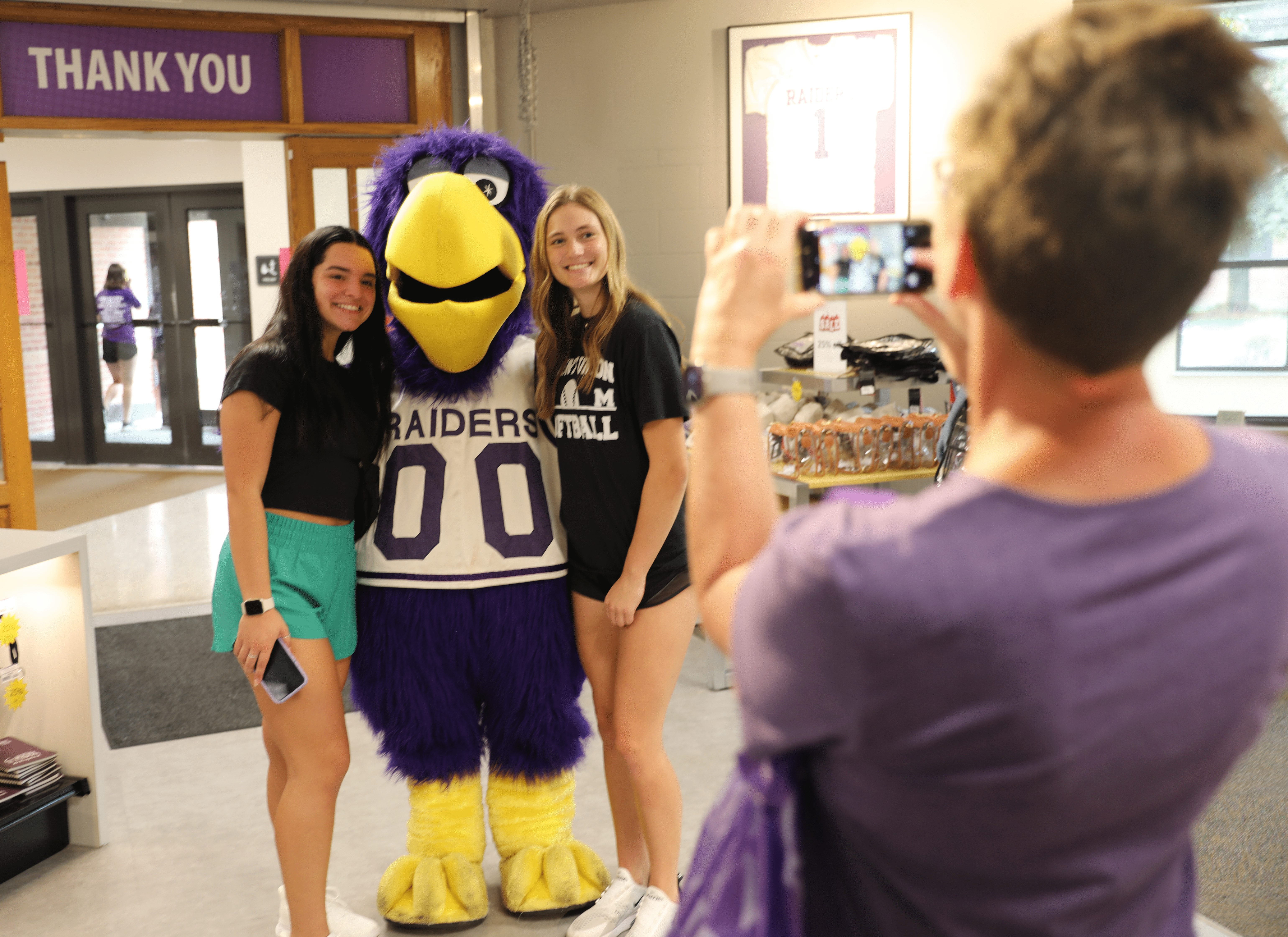 students taking photo with mascot