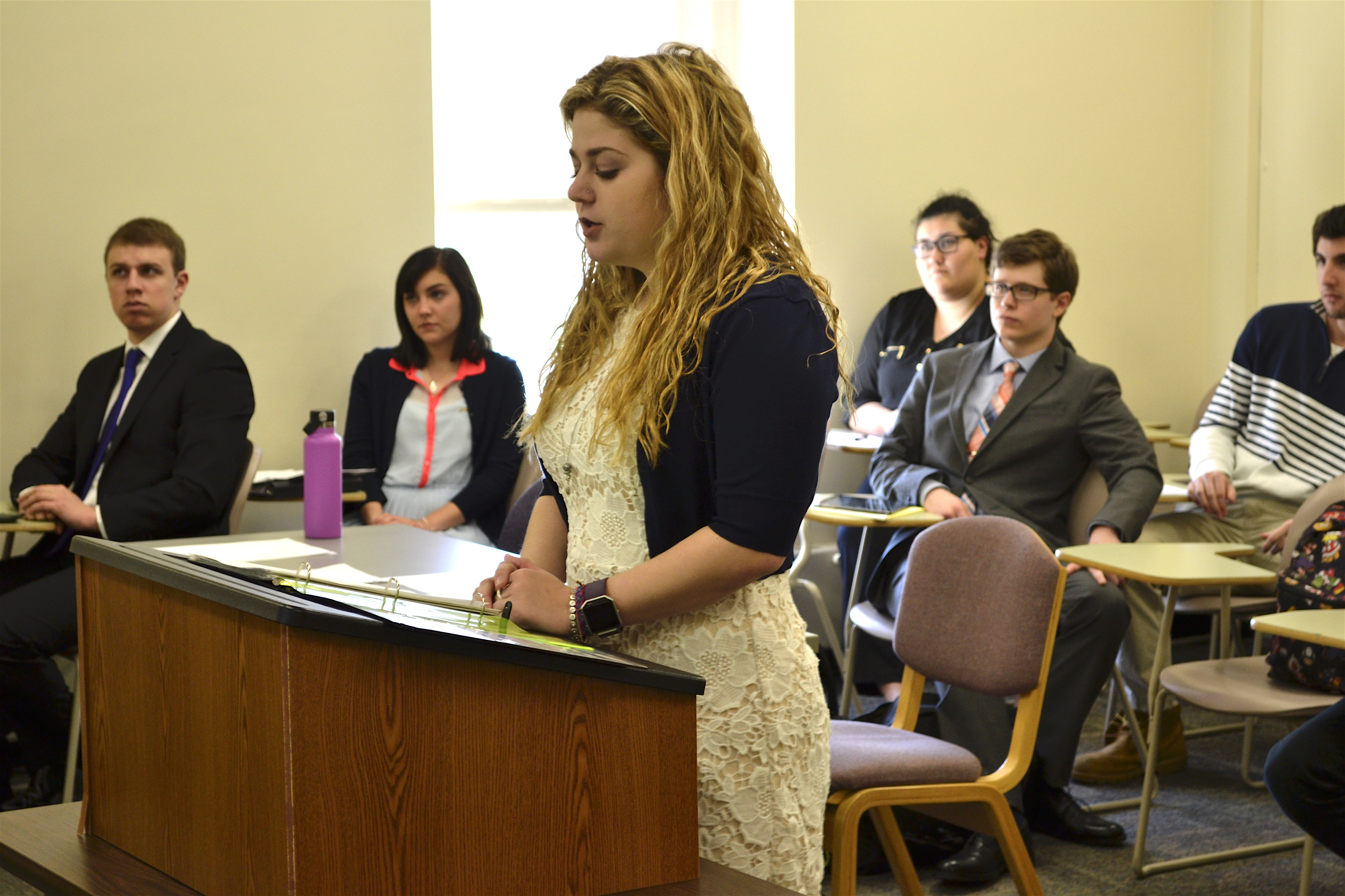 Student standing at a podium presenting to class