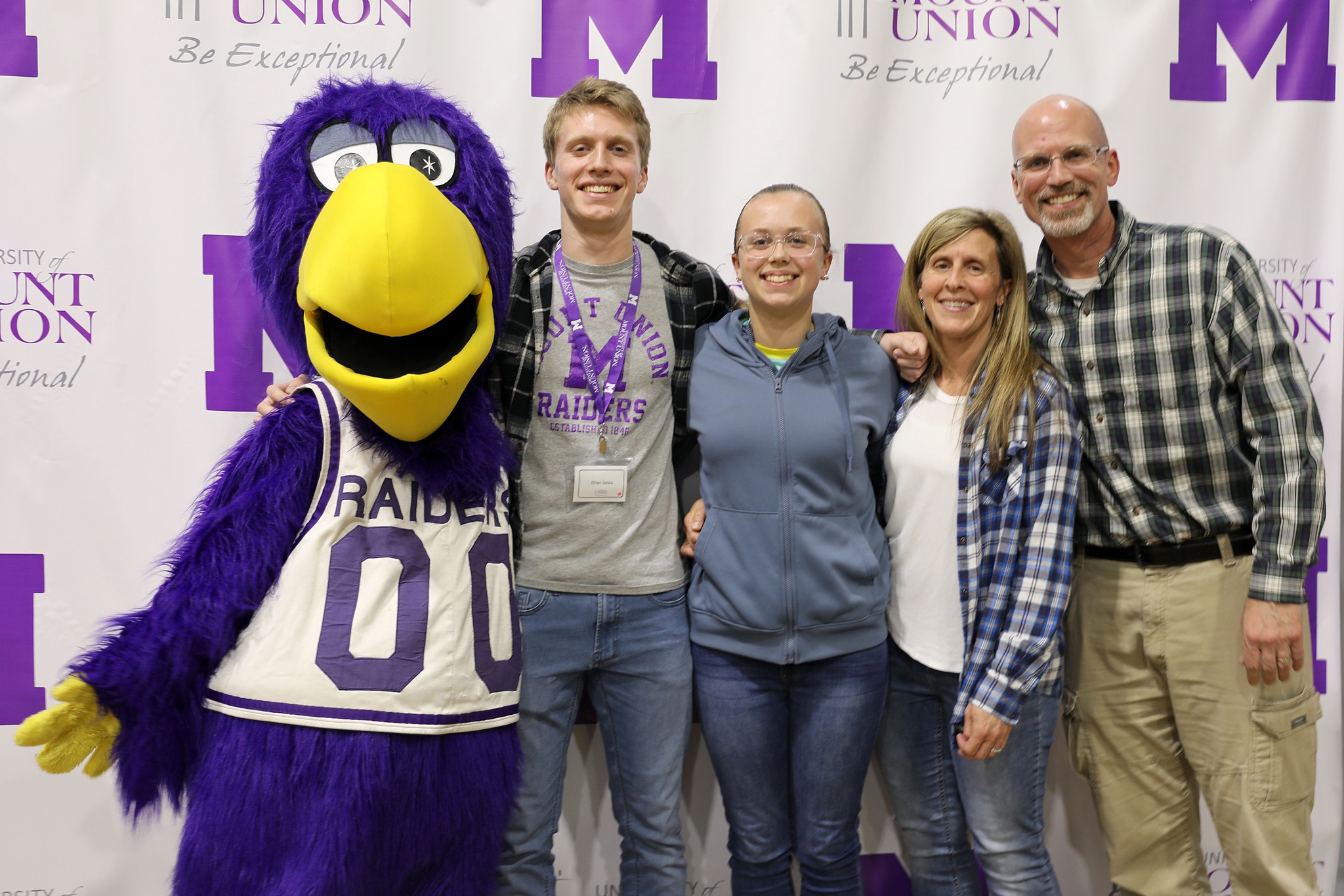 Purple Raider family posing with Mount Union mascot, MUcaw.
