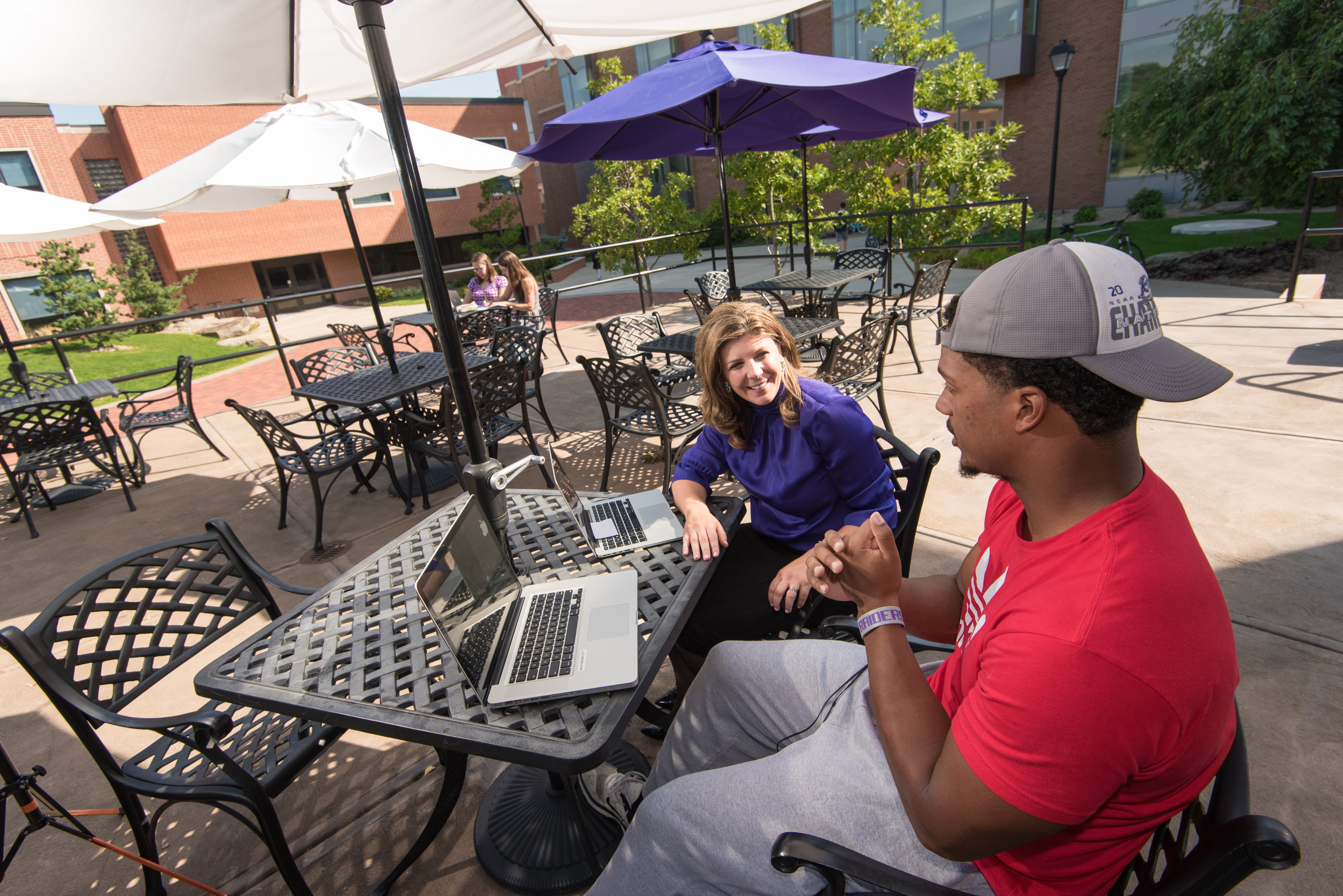 Student and professor using laptop on patio of library