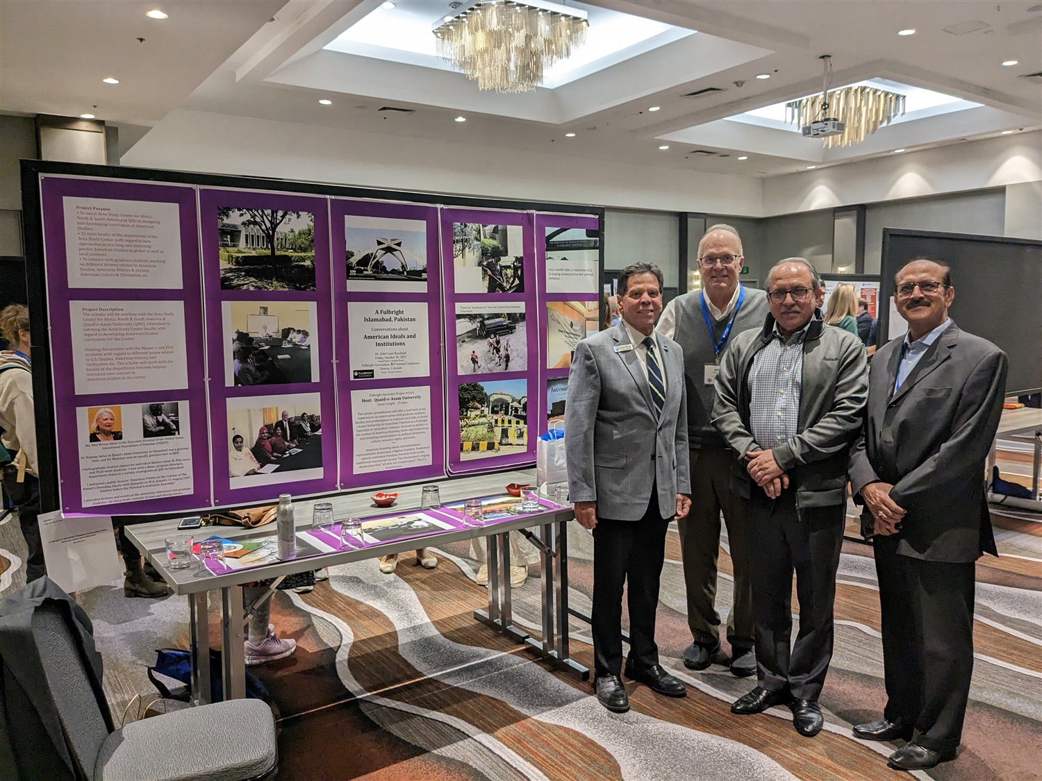 four men standing at conference poster presentation