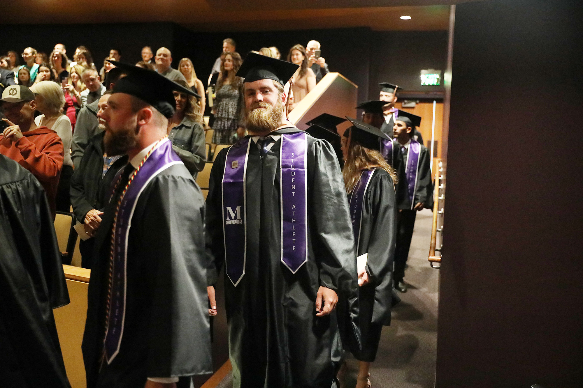student smiling at camera walking into ceremony