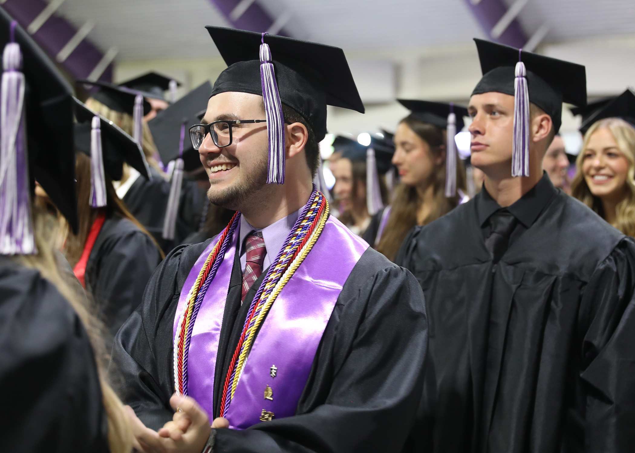 student wearing graduation regalia and smiling