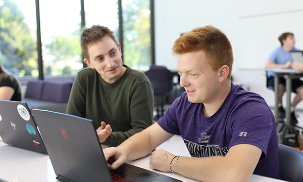 Two students in a data science class completing coursework on a laptop