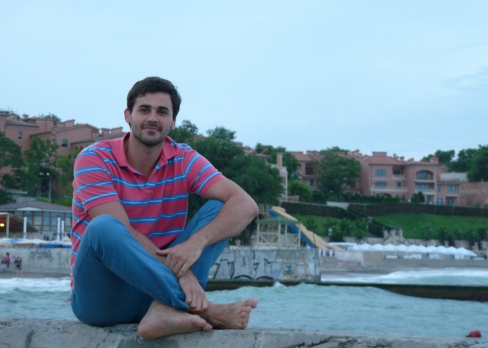 Student sitting in front of water and city