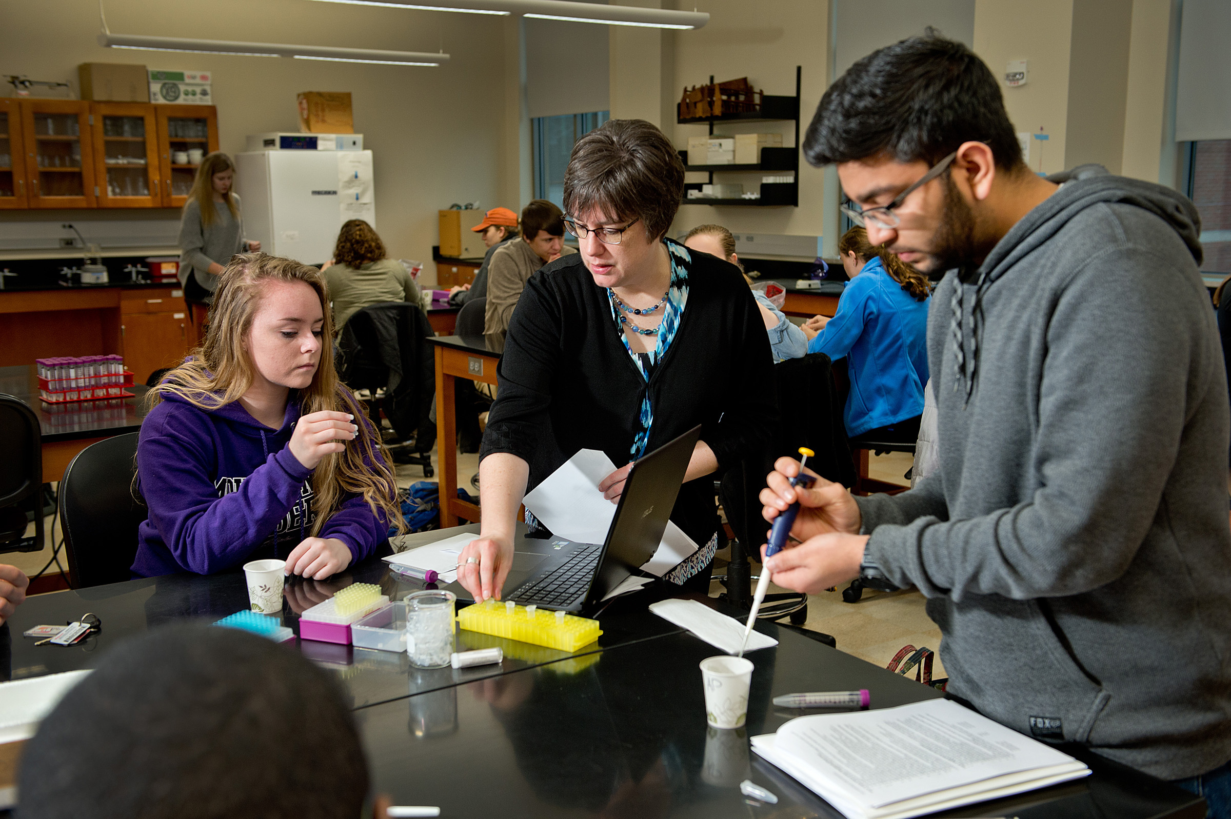 A faculty member assists two students with a lab assignment