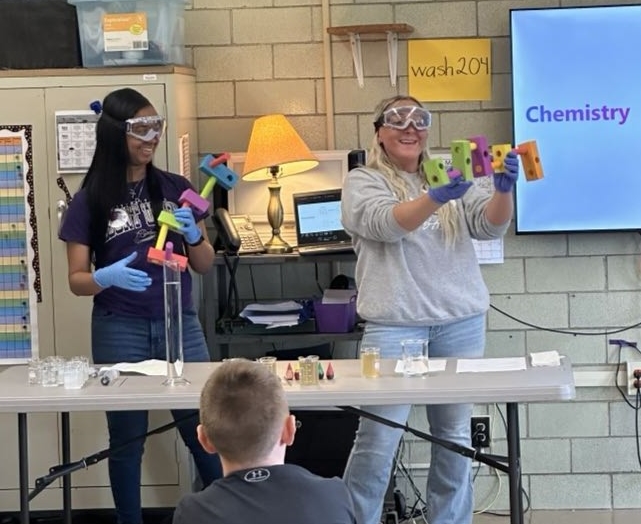 students doing experiments for elementary students looking on