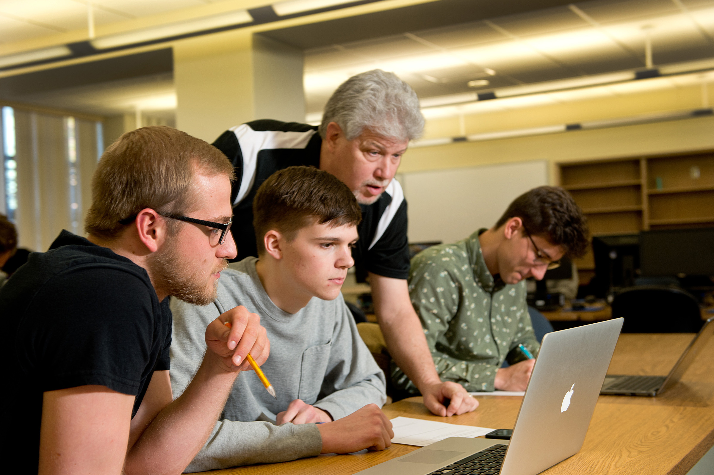 Professor teaching three students on their laptops