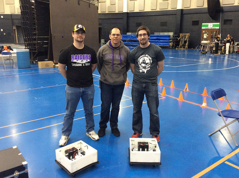 Students standing with robotic football players