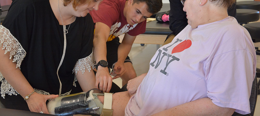 Engineering students and PT faculty member testing an adaptable prosthetic leg