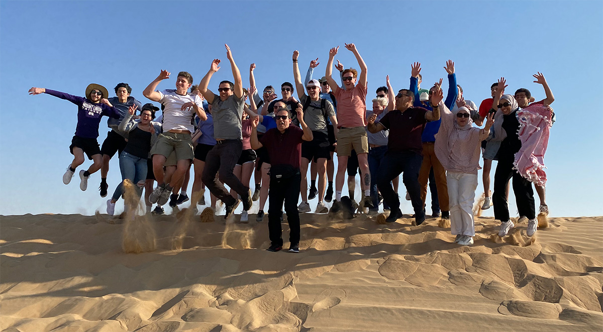 people jumping together on sand