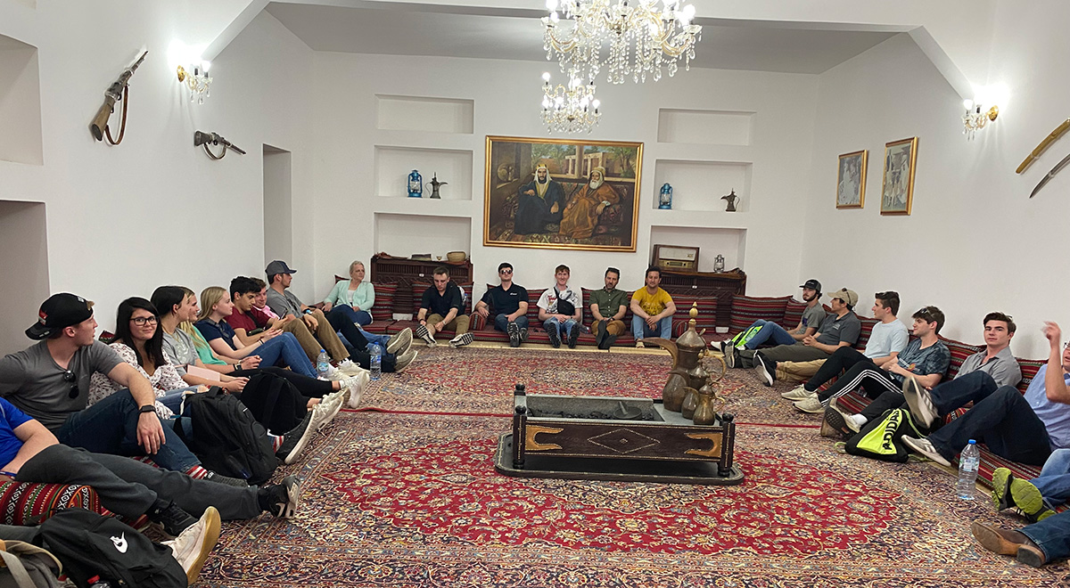 people sitting on large carpet in museum