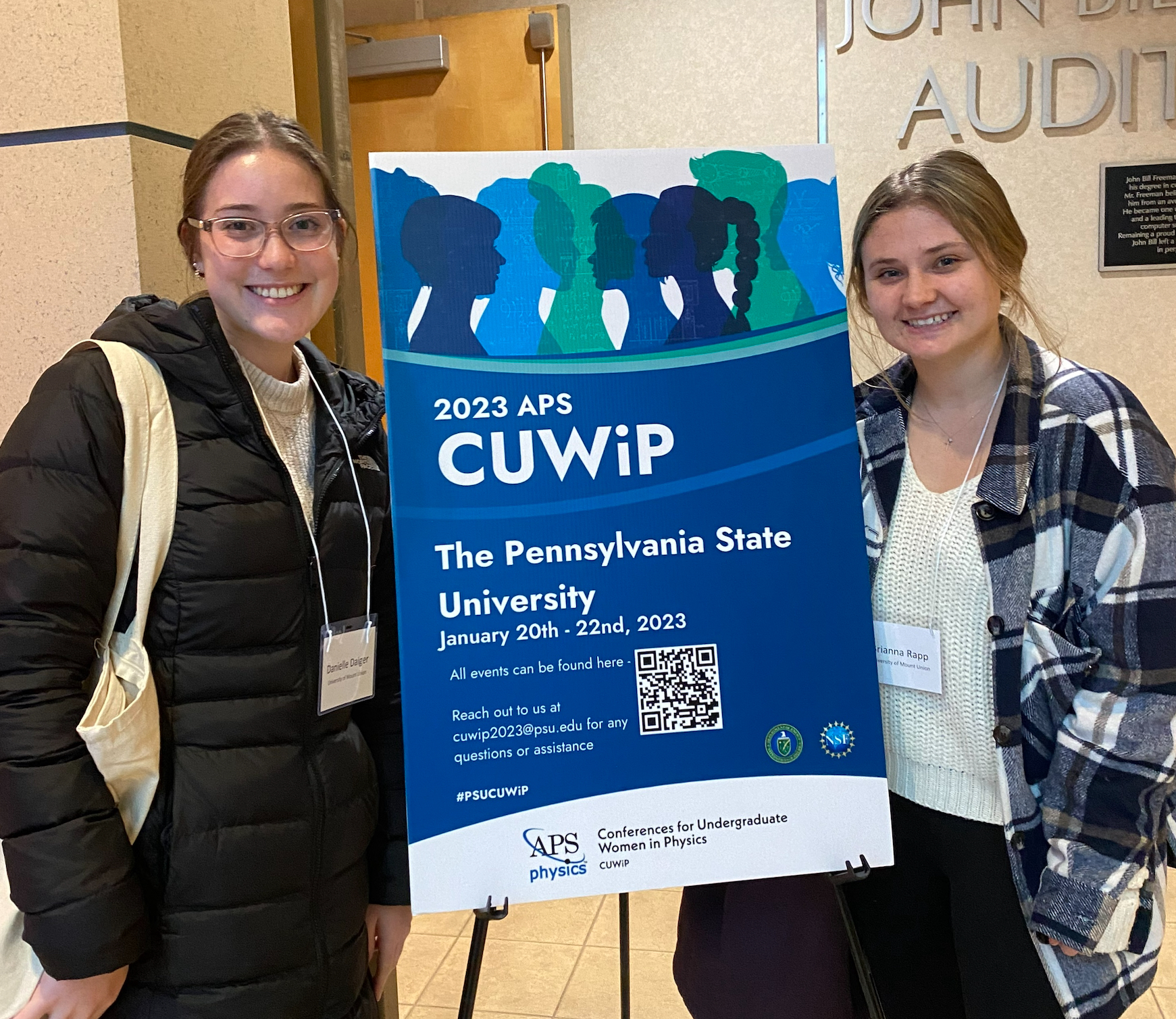 students standing at poster for physics conference