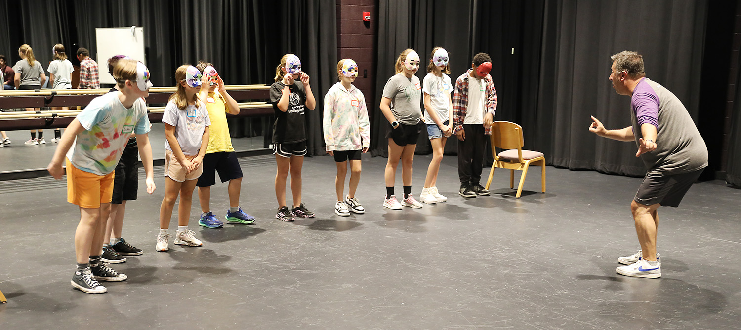 kevin kern engaging with group of students in masks in theater
