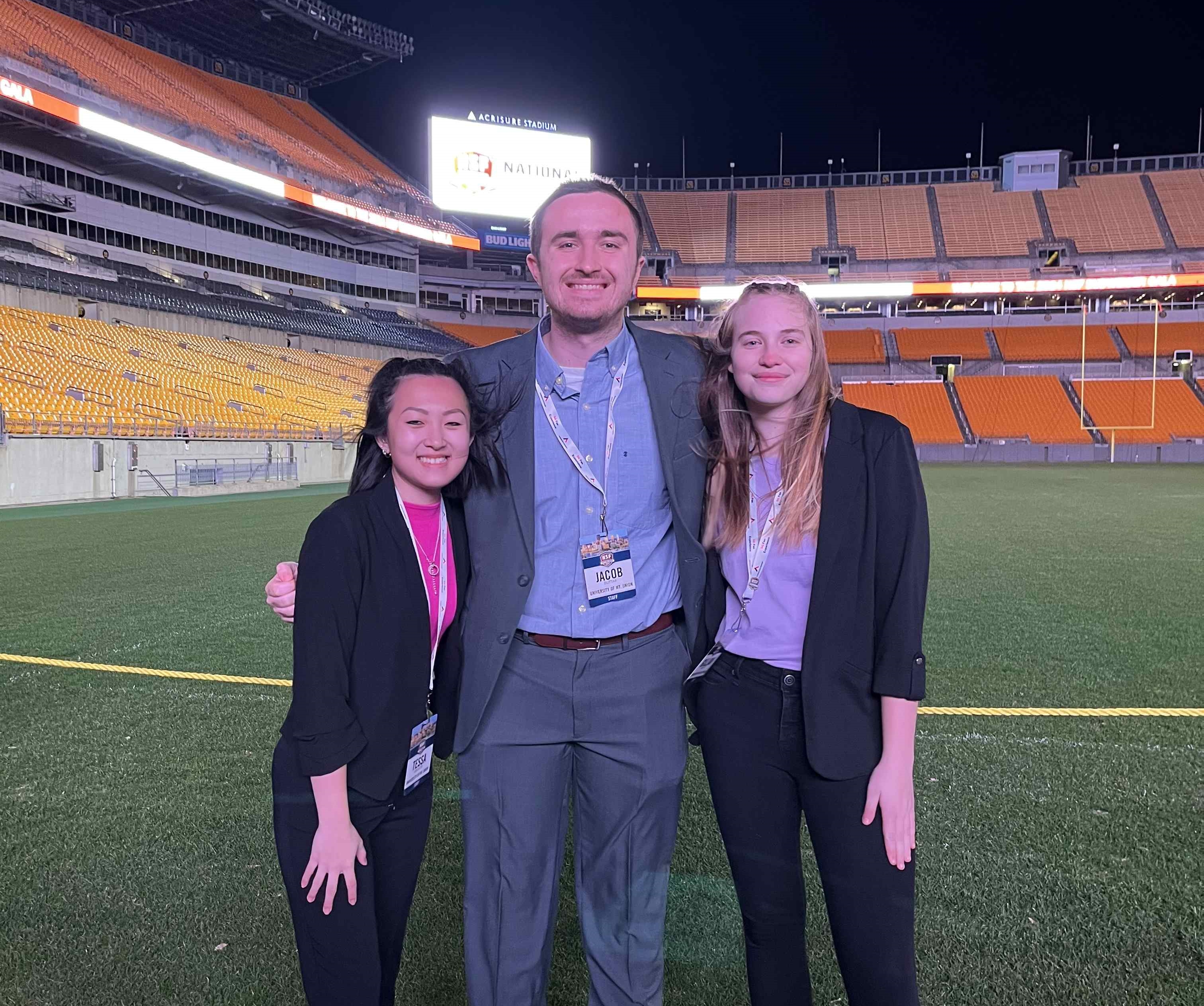 three mount union students standing on nfl field