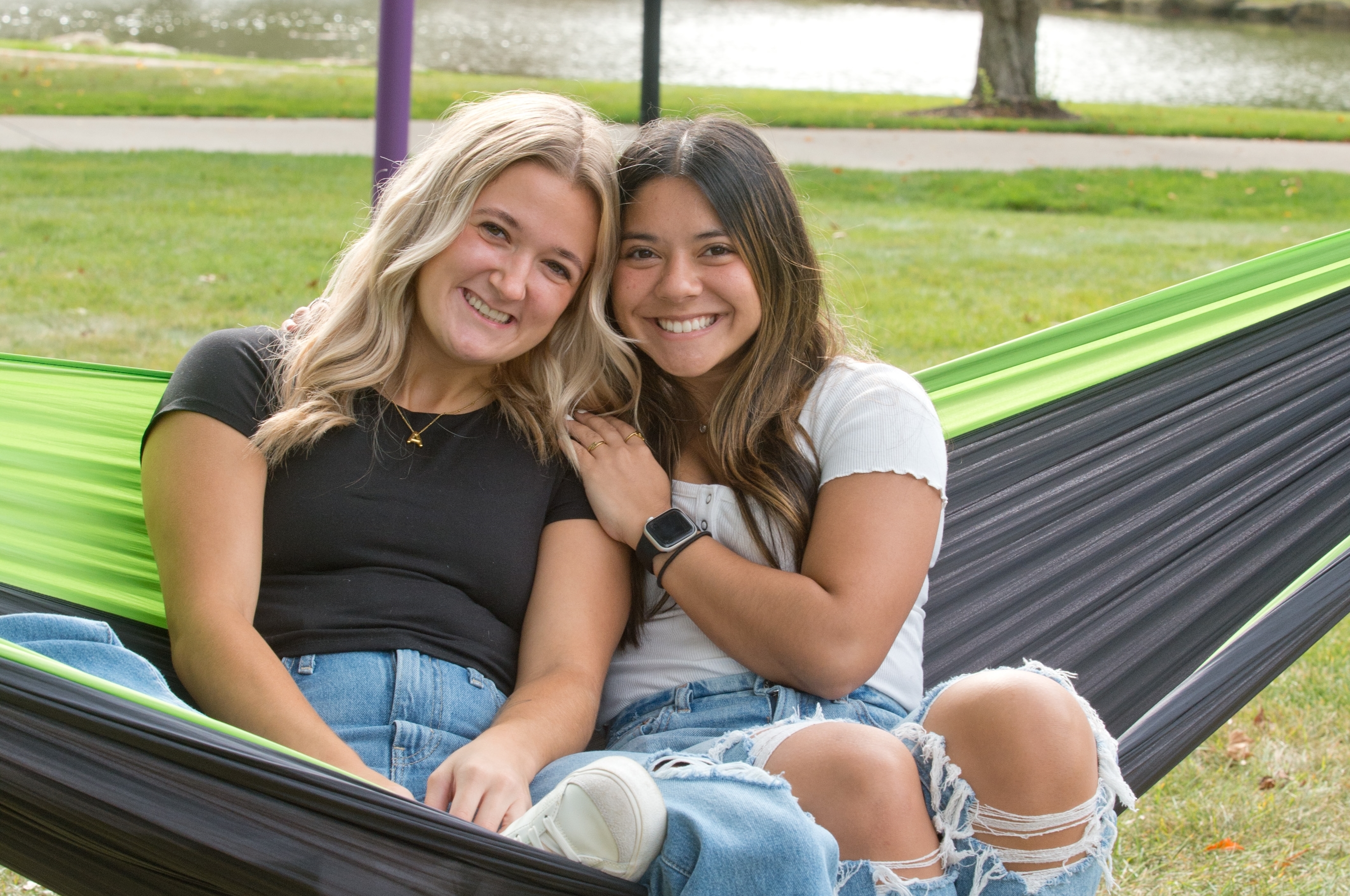 Mount Union students smiling on a hammock by the lakes.