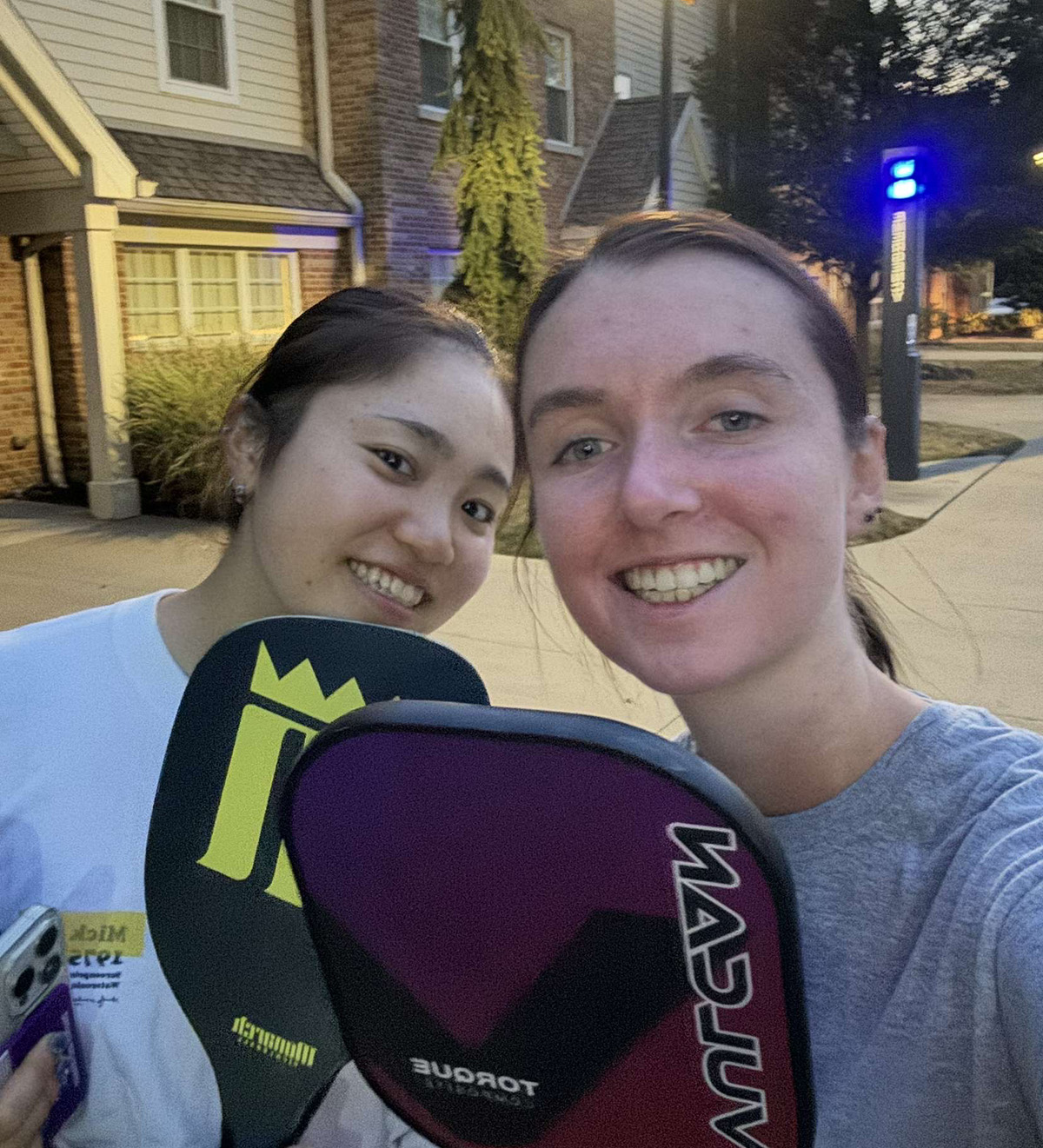 two students posing with pickleball paddles