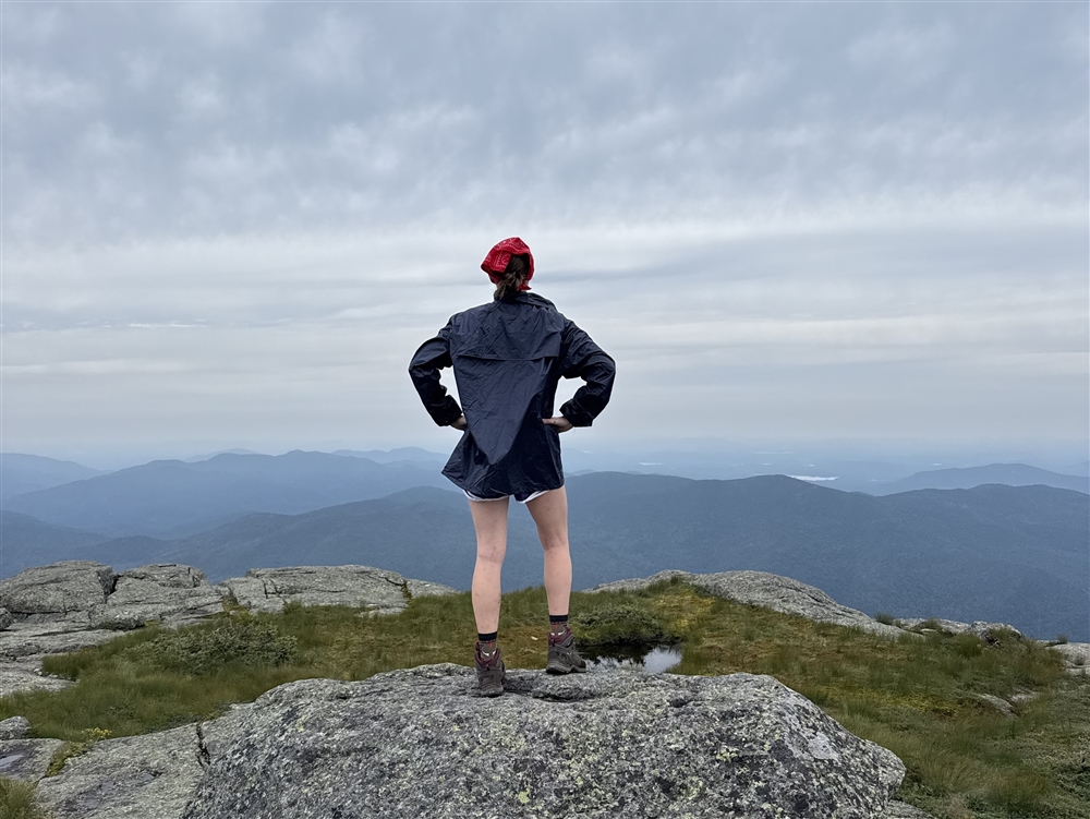 student standing on mountain looking over horizon