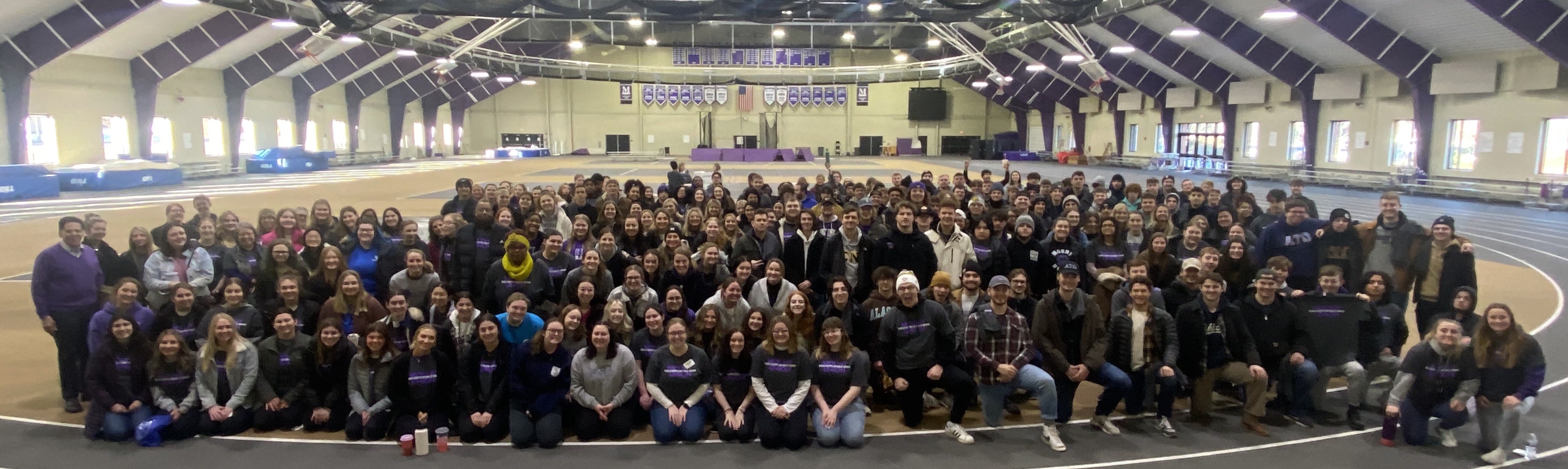 hundreds of volunteers in fieldhouse posed as a group