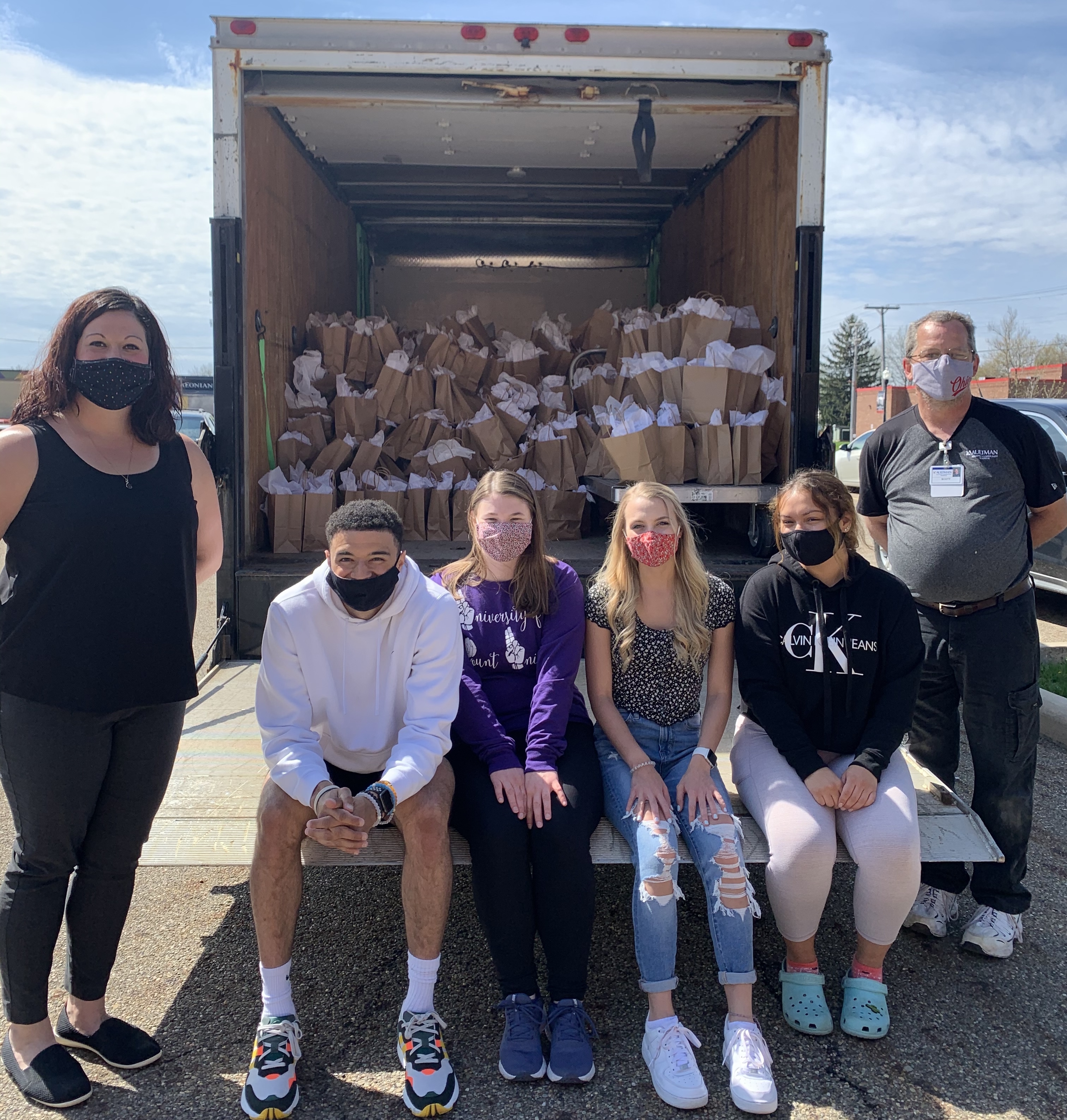 students in front of semi truck filled with bags