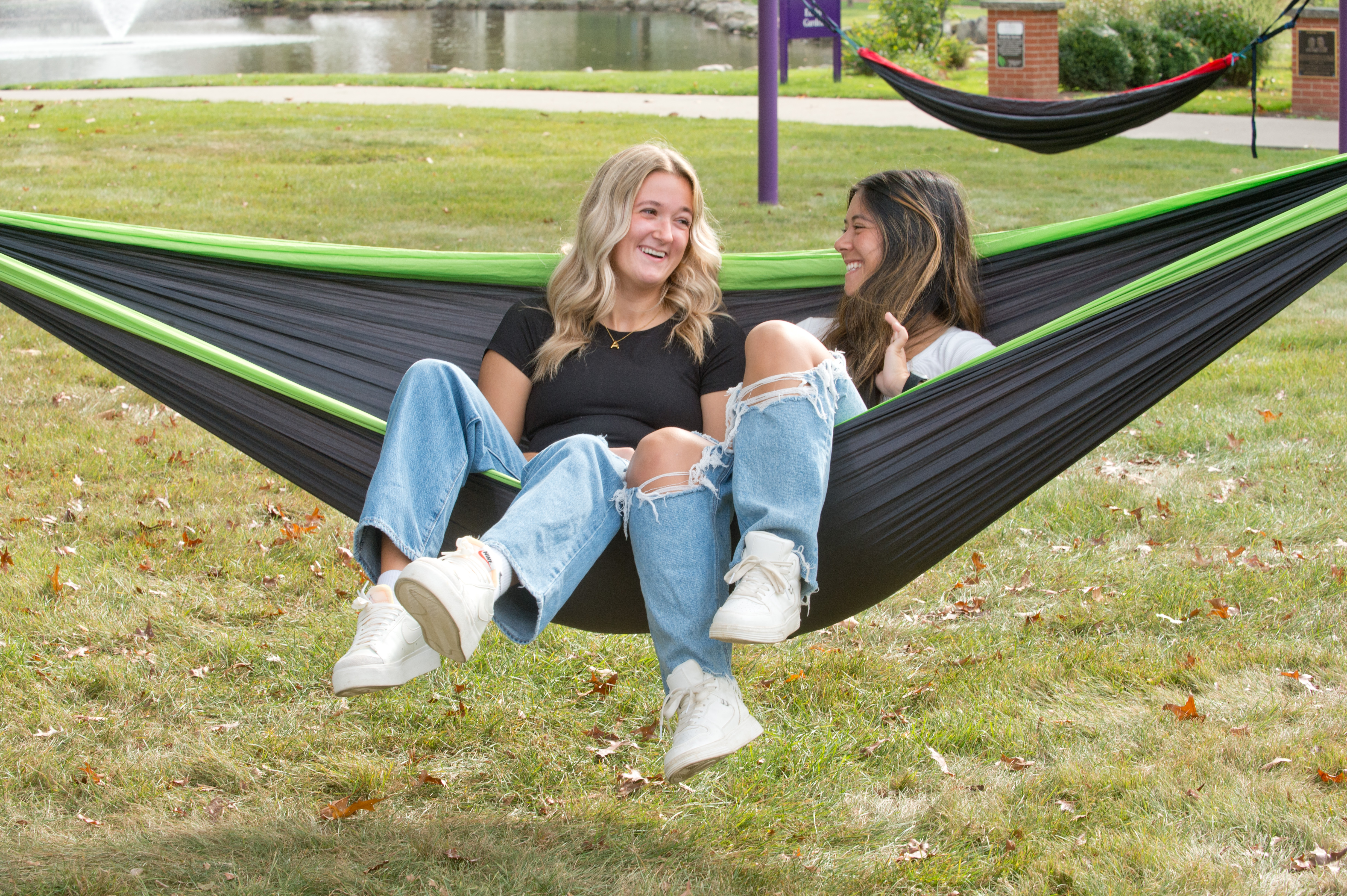 Smiling Mount Union students sitting together on a hammock at the Campus Lakes.
