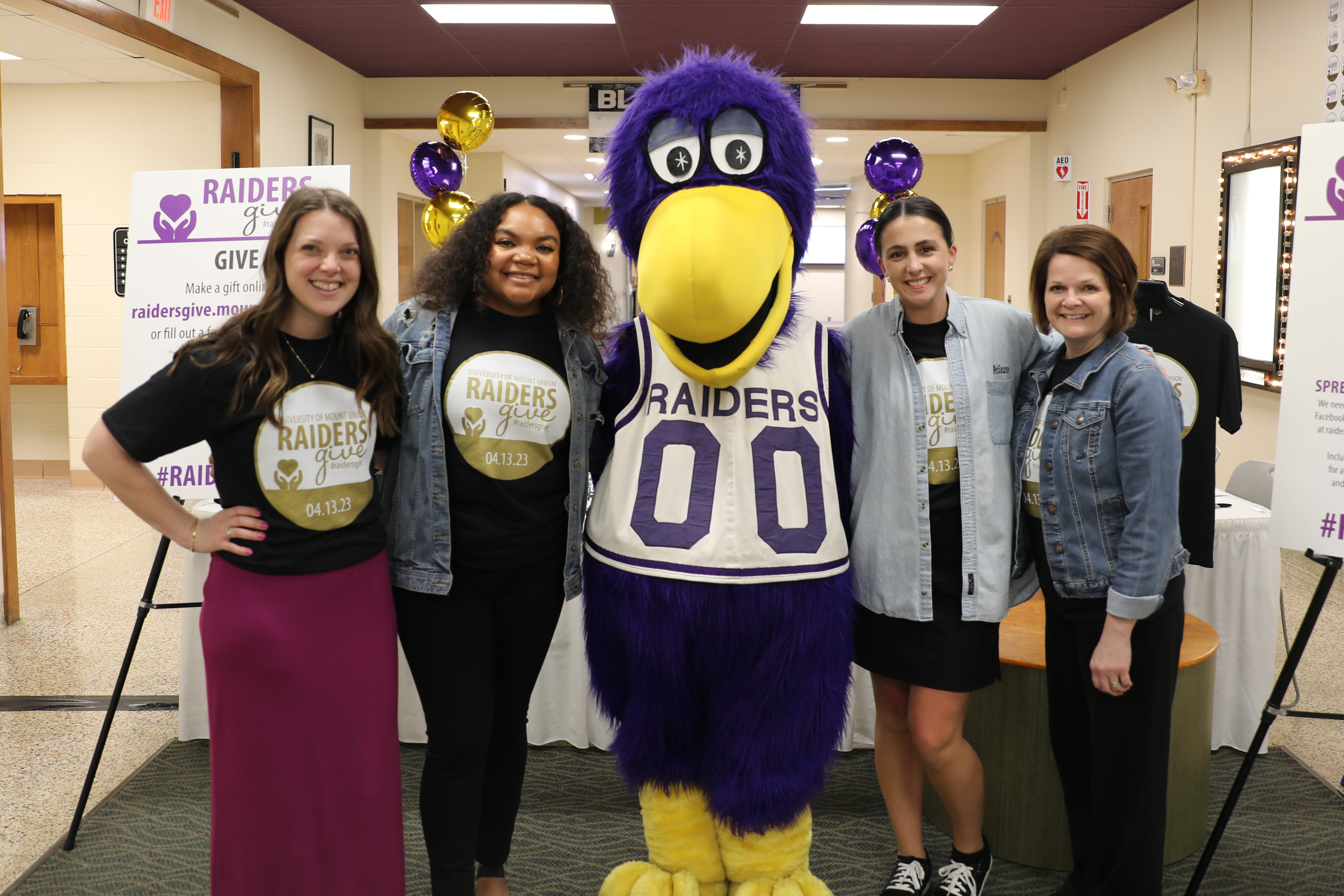 four women standing with mascot