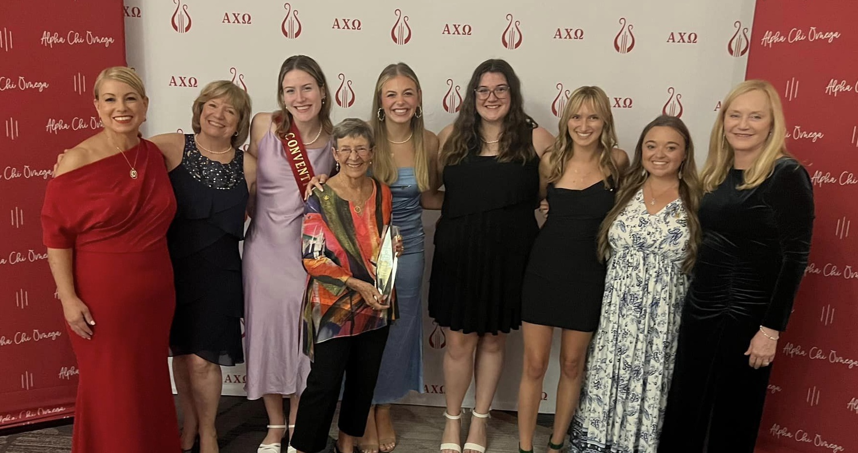 women of alpha chi omega standing with trophy at convention