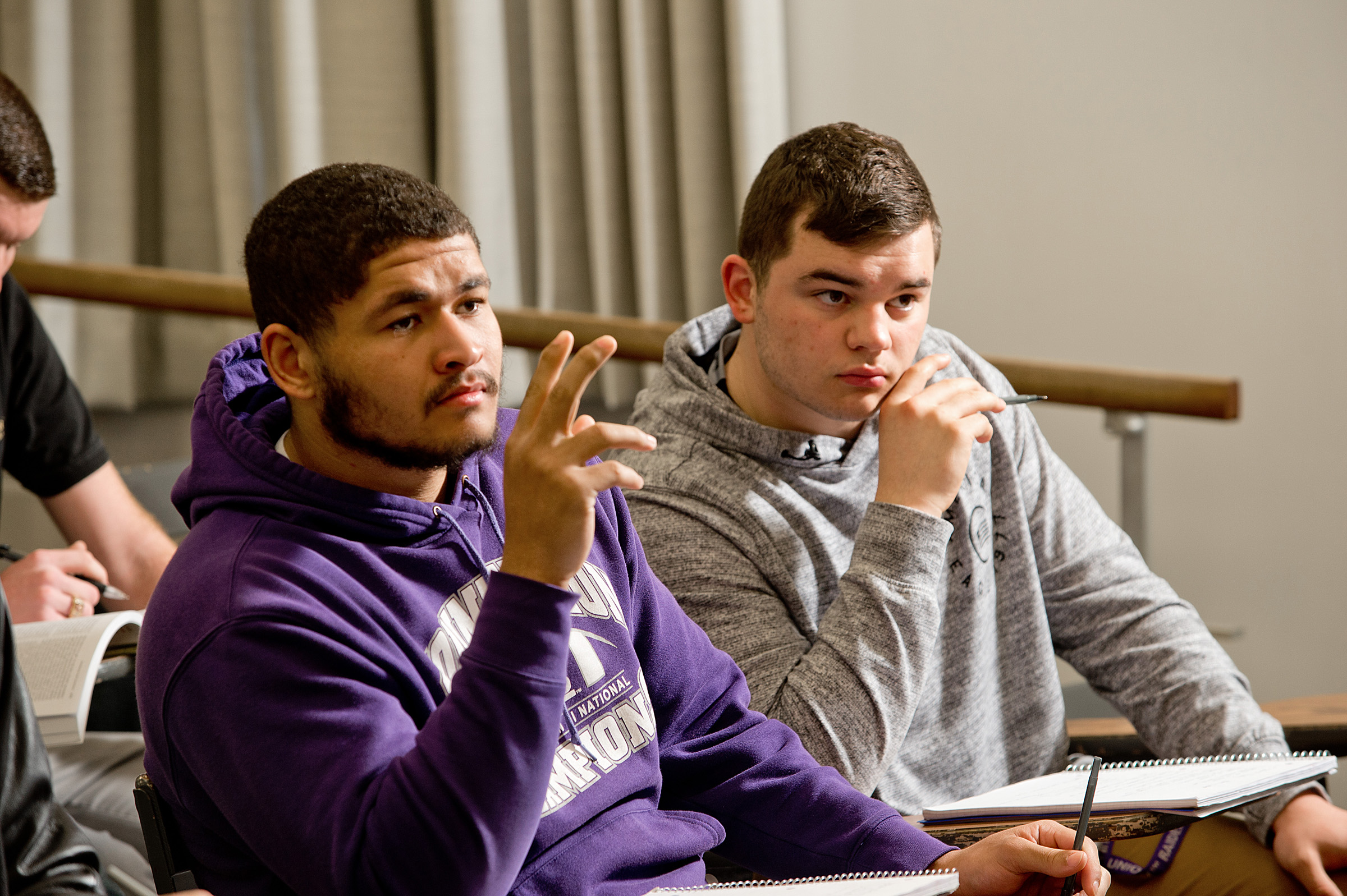 students raising hands in classroom