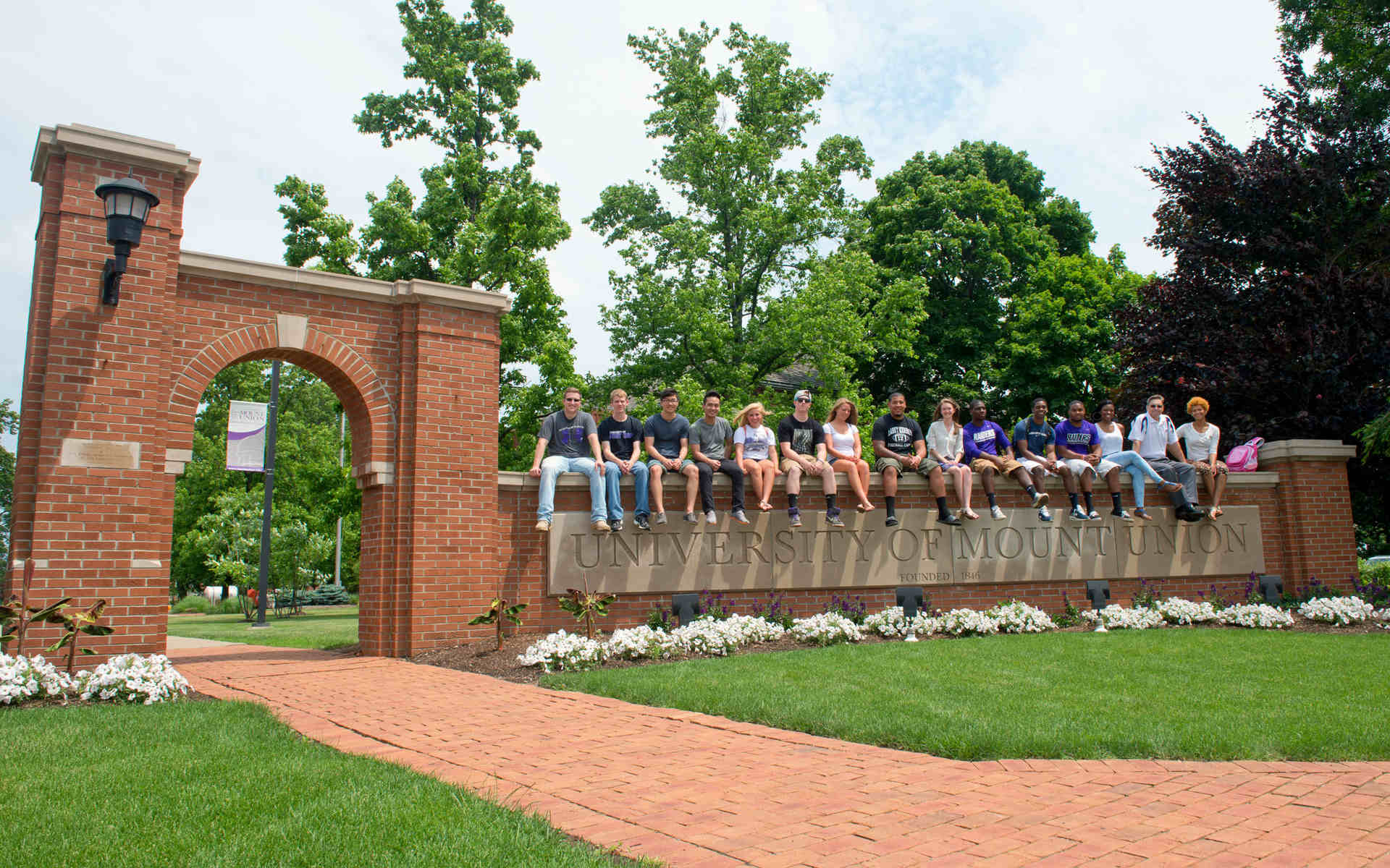 Mount Union students sitting on top of Mount Union gateway.