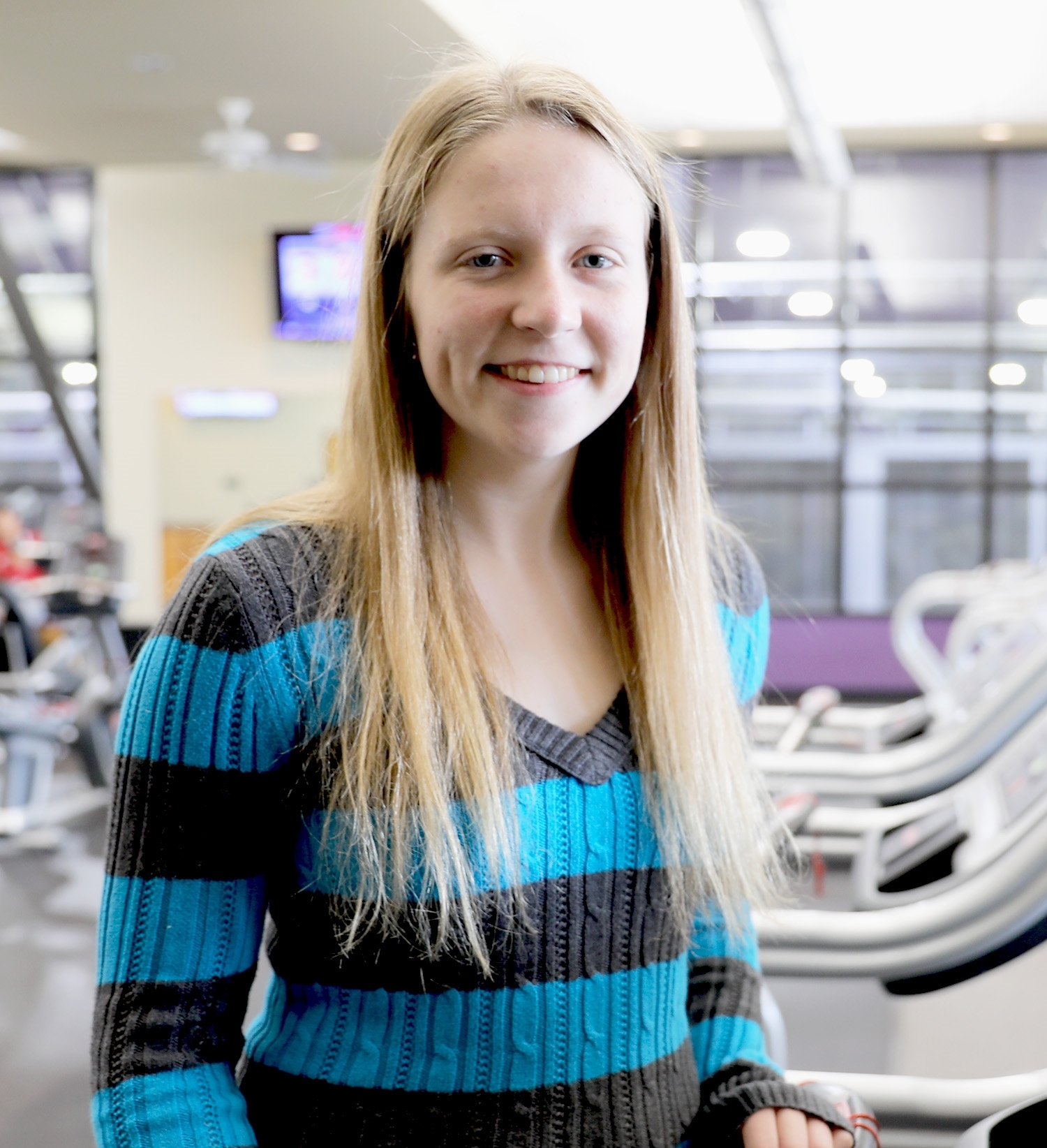 Hayley Maher stands smiling in front of exercise equipment