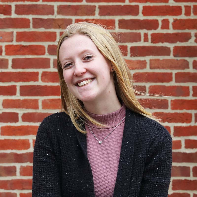 molly hudson headshot in front of brick wall